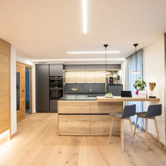 Moderne Küche mit Holzdetails, Kochinsel, Hockern und großen Fenstern mit Vorhängen