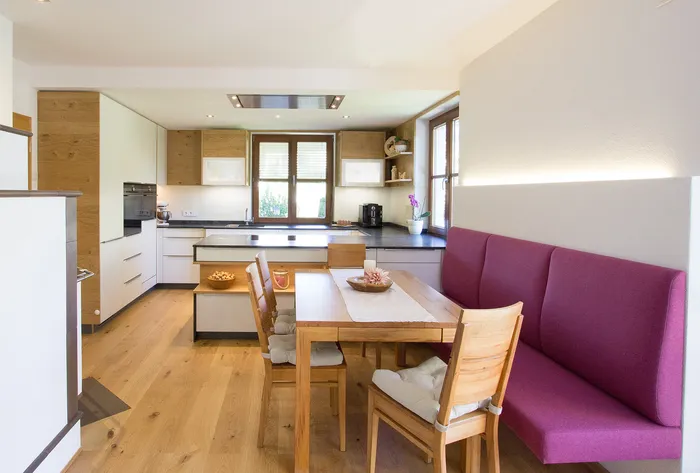 Moderne Wohnküche mit Holzboden, Einbauküche und Essbereich mit pinker Bank