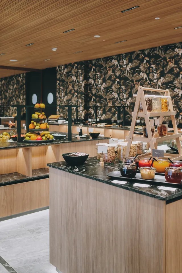 Modernes Frühstücksbuffet mit frischem Obst, Müsli, Marmelade und Säften in stilvollem Hotelrestaurant