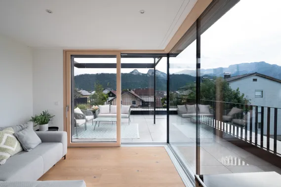 Modernes Wohnzimmer mit Glasfront und Blick auf Terrasse und Berge