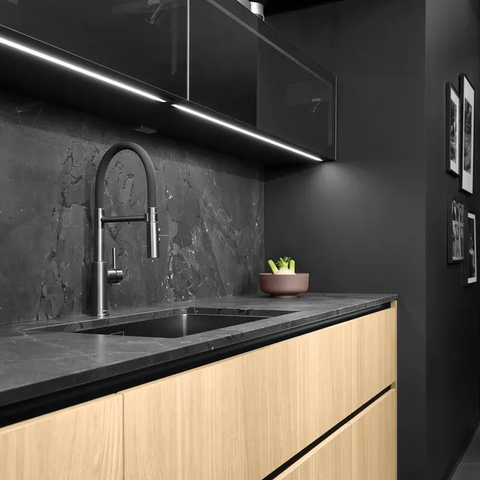 Moderne schwarze Küche mit Holzunterschränken, Steinspüle und LED-Beleuchtung