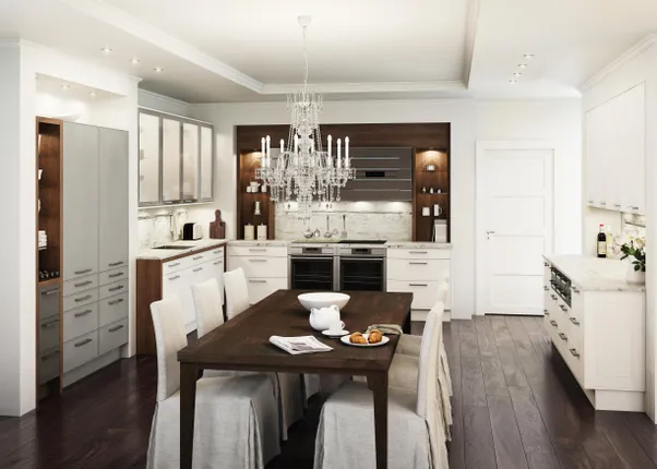 Moderne weiße Küche mit Holzakzenten, Kronleuchter und Esstisch mit gedecktem Frühstück