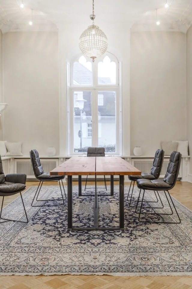 Heller Konferenzraum mit Holztisch, modernen Stühlen und orientalischem Teppich