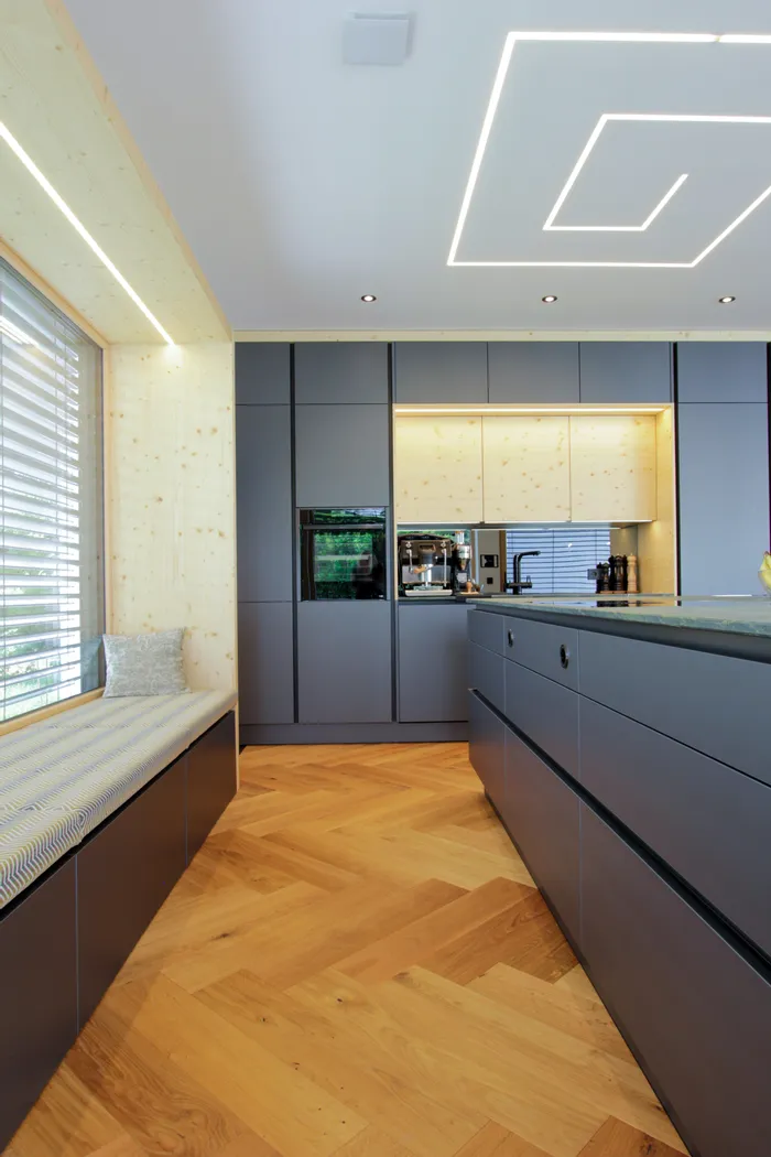 Moderne Küche mit grauen Schränken, Holzverkleidung und Fischgrätparkett