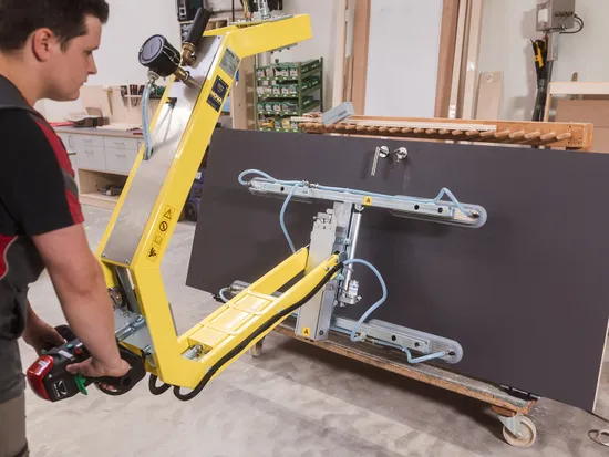Handwerker bedient Vakuumhebegerät zum Heben großer Platten in einer Werkstatt