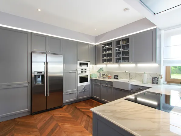 Moderne Einbauküche mit grauen Schränken, Marmorarbeitsplatte und Holzboden