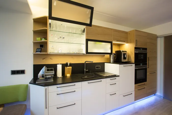 Moderne Einbauküche mit Holzfronten, schwarzer Arbeitsplatte und integrierten Elektrogeräten