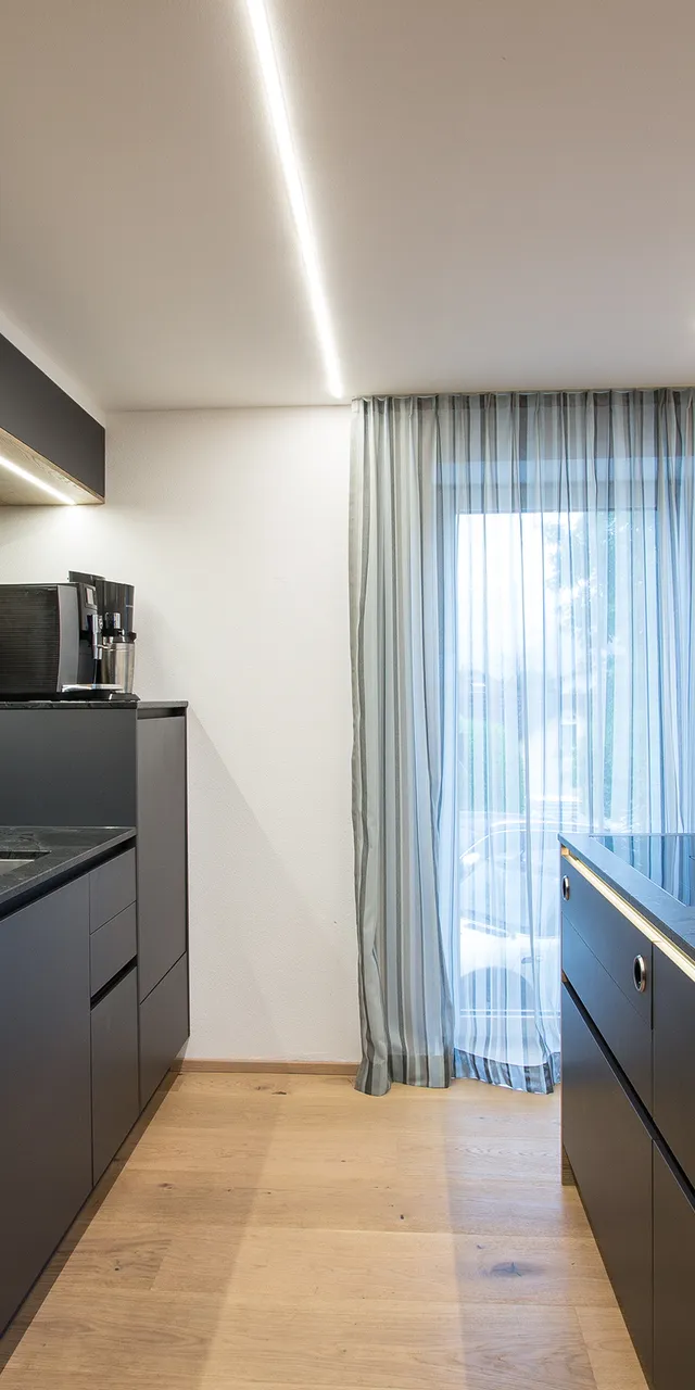 Moderne Küche mit schwarzen Schränken, Holzdetails und Kücheninsel mit Induktionskochfeld