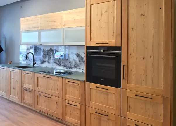 Moderne Einbauküche aus hellem Holz mit schwarzem Wasserhahn und Bergpanorama als Rückwand