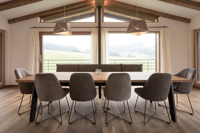 Moderner Essbereich mit Holztisch, gepolsterten Stühlen und Panoramafenstern mit Bergblick