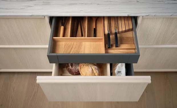 Geöffnete Küchenschubladen mit Holzbesteckeinsatz, Messern, Brot und Salzpackung