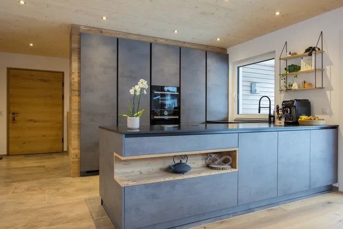 Moderne Küche mit grauen Schränken, Kochinsel und eingebautem Ofen