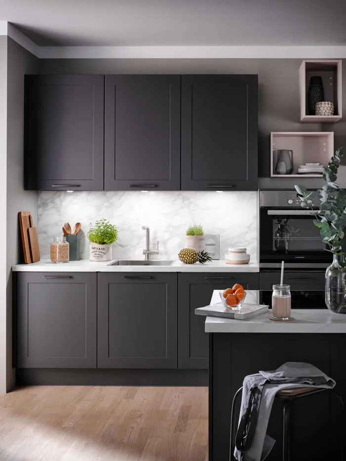 Moderne Küche mit dunklen Schränken, Marmor-Rückwand und frischen Zutaten auf der Theke