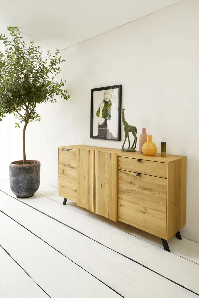 Modernes Sideboard aus Eiche mit Dekorationen und Topfpflanze in hell eingerichteter Wohnung