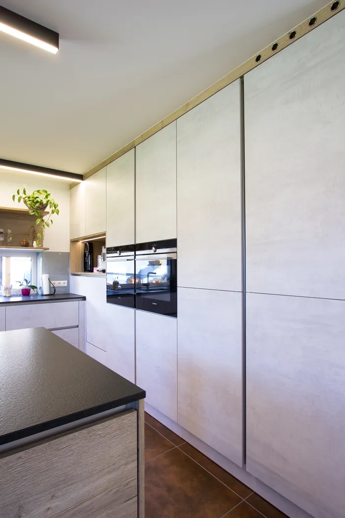 Moderne Einbauküche mit hellen Fronten, schwarzen Geräten und Kücheninsel