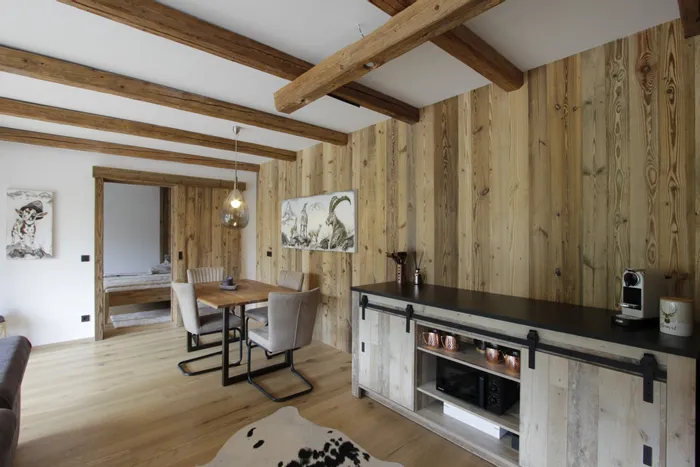 Modernes Esszimmer im Alpenstil mit Holzwänden, Holzbalken und rustikaler Einrichtung