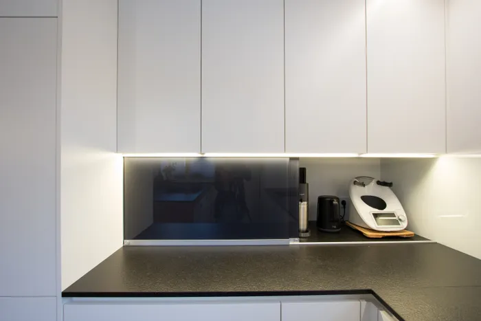 Moderne weiße Einbauküche mit Küchenmaschine, Wasserkocher und schwarzer Arbeitsfläche