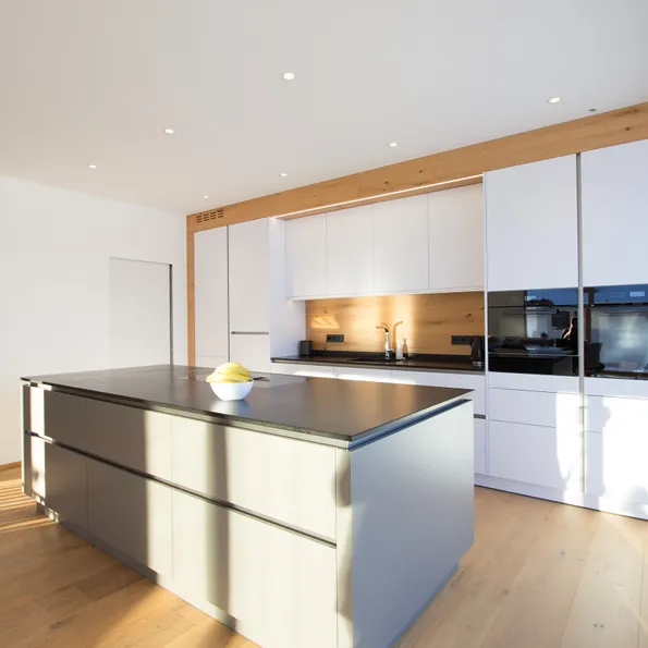 Moderne weiße Einbauküche mit Kochinsel, Holzverkleidung und natürlichem Lichteinfall