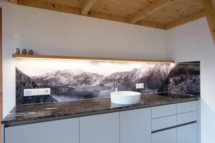 Moderne Küchenzeile mit Waschbecken und Alpen-Panoramabild als Rückwand