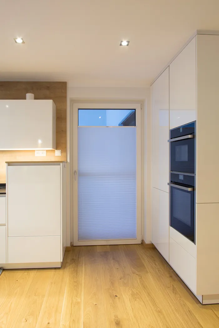 Moderne weiße Küche mit Holzfußboden und offenem Vorratsschrank mit Lebensmitteln