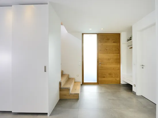 Moderner Hausflur mit Holztür, Natursteinboden und eingebauter Garderobe