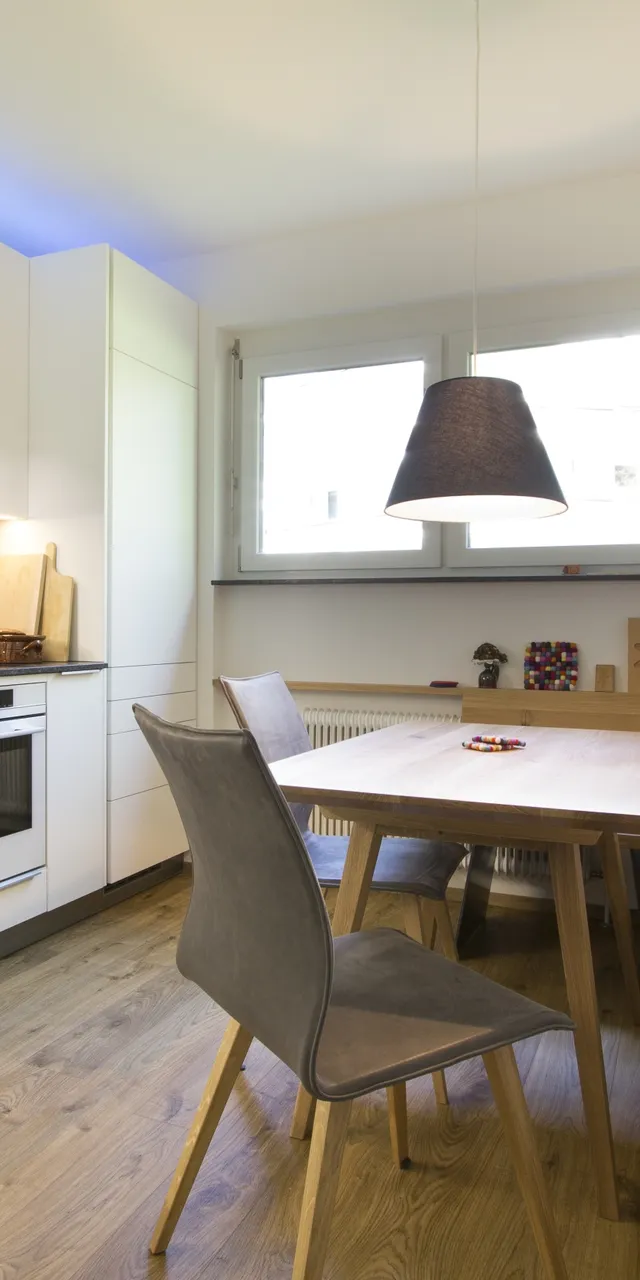 Moderne Küche mit Essbereich, Holzbank und blauen Akzenten auf hellem Holzboden