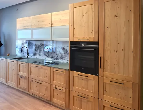 Moderne Einbauküche aus hellem Holz mit schwarzem Wasserhahn und Bergpanorama als Rückwand