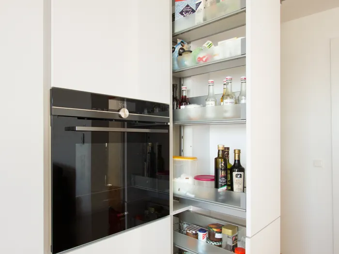Geöffneter Apothekerschrank in moderner Küche mit Lebensmitteln und Getränken