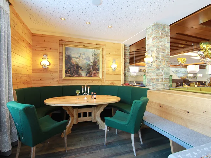 Gemütliche Sitzecke in einem alpenländischen Restaurant mit Holzwänden und grüner Polsterbank