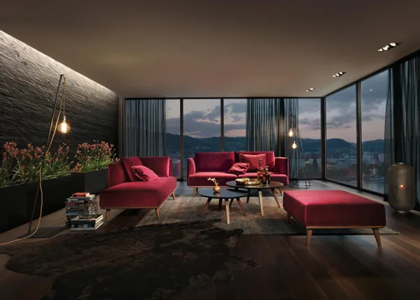 Modernes Wohnzimmer mit weinroten Samtmöbeln, dunklem Holzboden und Panoramablick bei Sonnenuntergang