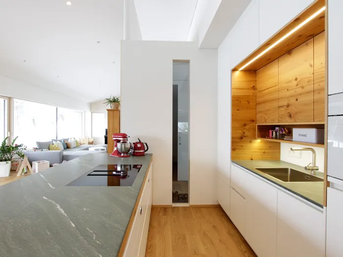 Moderne offene Küche mit Holzverkleidung, Induktionsherd und roten Küchengeräten