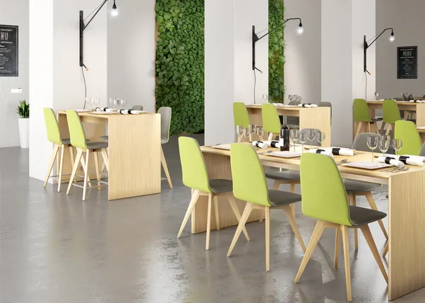 Modernes Restaurant mit Holzmöbeln, grünen Stühlen und vertikaler Pflanzenwand