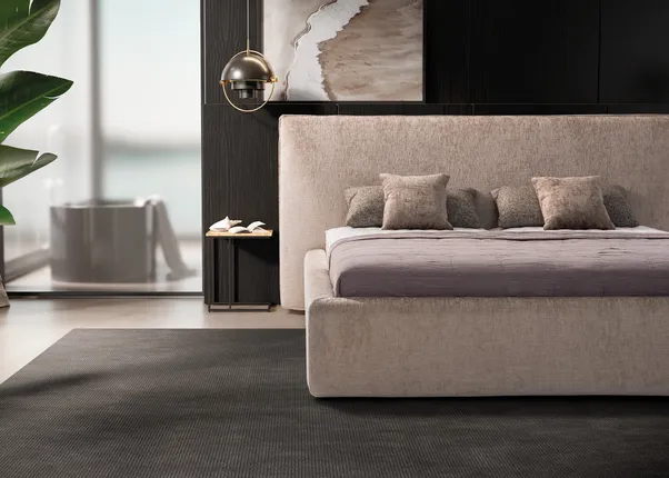Modernes Schlafzimmer mit Polsterbett, dunkler Wandverkleidung und Blick auf freistehende Badewanne