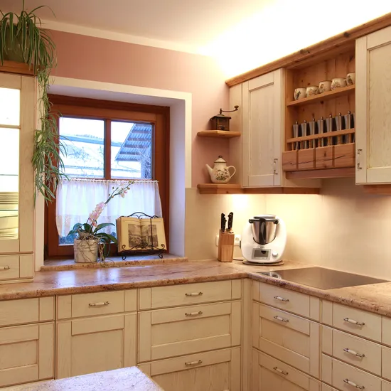 Moderne Landhausküche mit hellen Holzmöbeln, Arbeitsplatten aus Stein und Küchenmaschinen