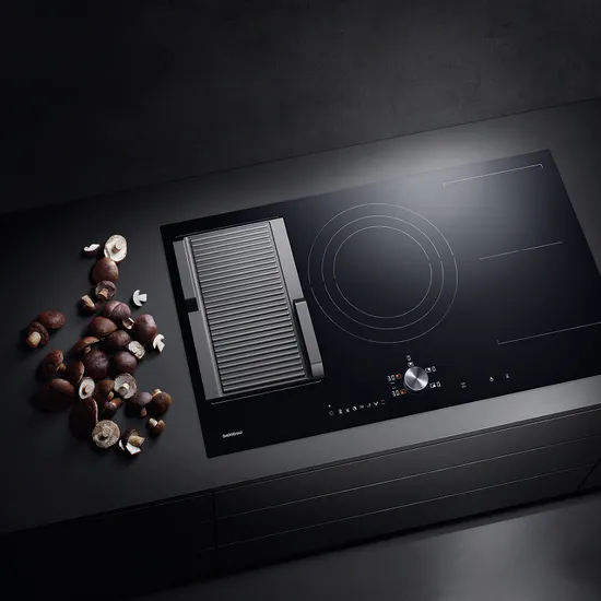 Schwarzes Induktionskochfeld mit integriertem Grill und geschnittenen braunen Champignons