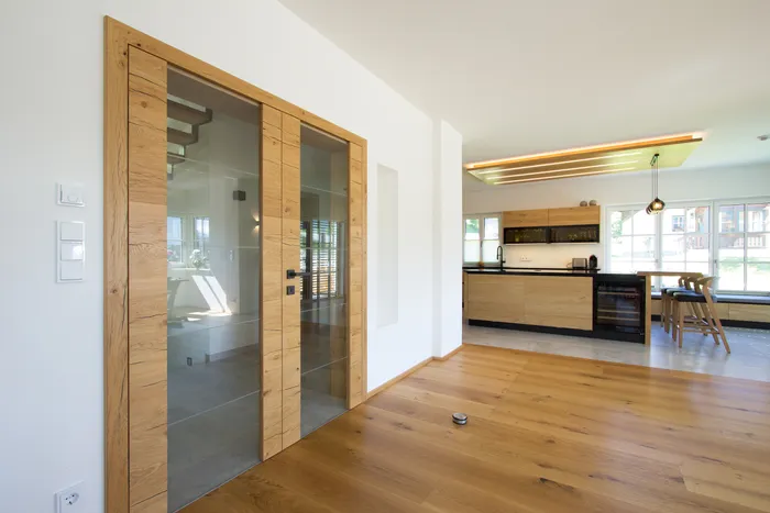 Moderne offene Küche mit Holzverkleidung, Barhockern und Glastüren im Wohnbereich