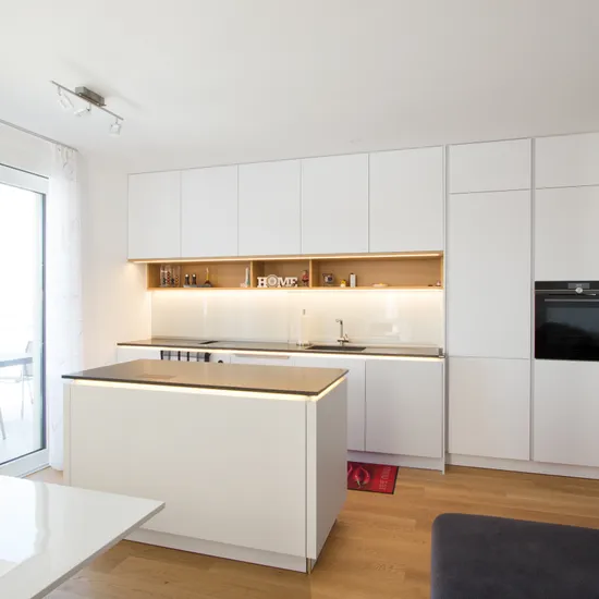 Moderne weiße Einbauküche mit Kochinsel und Holzfußboden