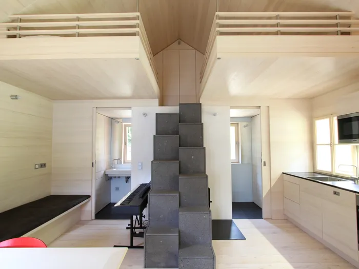 Modernes Tiny House mit Holzinterieur, Küchenzeile, Schlafboden und zentraler Treppe