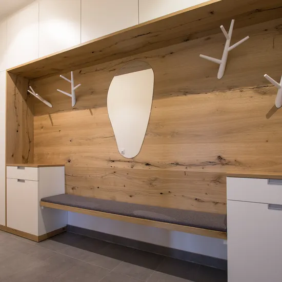 Moderne Garderobe mit Holzverkleidung, Bank, Spiegel und weißen Haken
