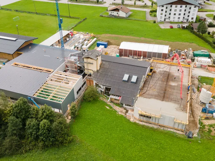 Luftaufnahme einer großen Baustelle neben einem Sportgelände in einer ländlichen Gegend