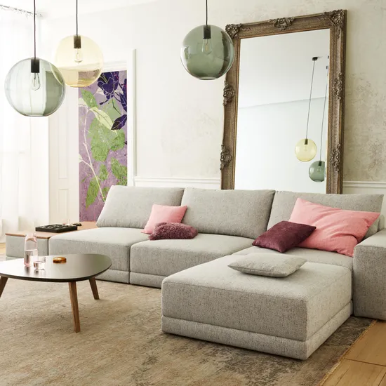 Modernes Wohnzimmer mit grauem Ecksofa, bunten Kissen und großem Spiegel an der Wand