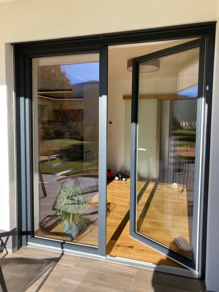 Offene Terrassentür mit Glasrahmen, Blick ins Wohnzimmer mit Spielzeug und Holzboden