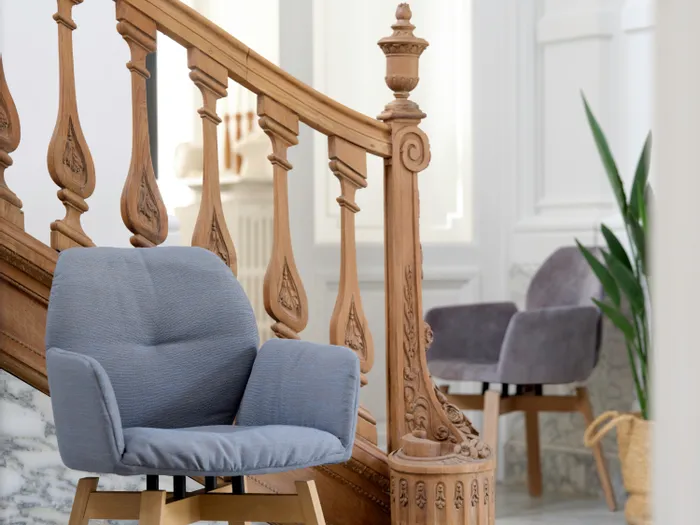 Moderne gepolsterte Stühle vor einer dekorativen Holztreppe in elegantem Innenraum