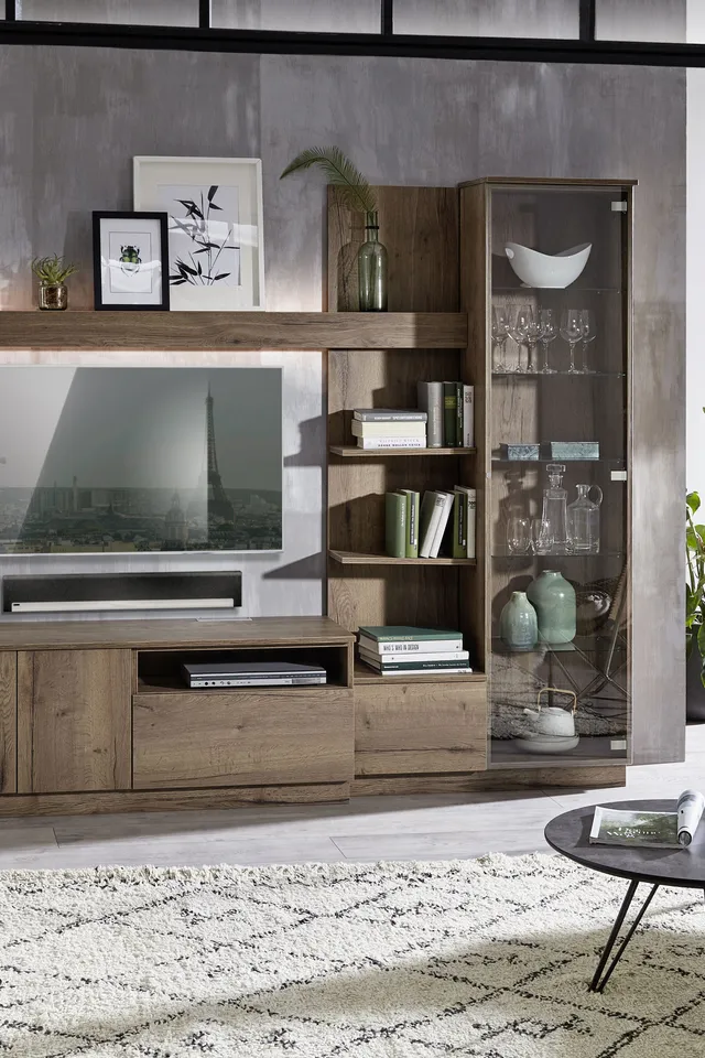 Modernes Wohnzimmer mit Holz-Wohnwand, Glasvitrine und runder Couchtisch auf Teppich