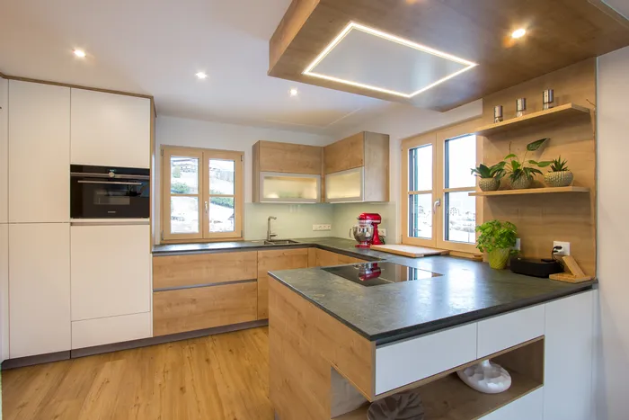 Moderne Einbauküche mit Holzfronten, Kochinsel, Induktionsfeld und roten Küchenmixer