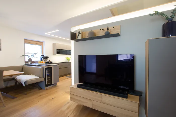 Modernes Wohnzimmer mit Flachbildfernseher, offener Küche und Holzfußboden