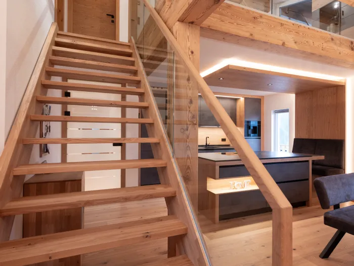 Moderne Holztreppe mit Glasgeländer in offenem Wohnbereich mit Küche und Obergeschoss