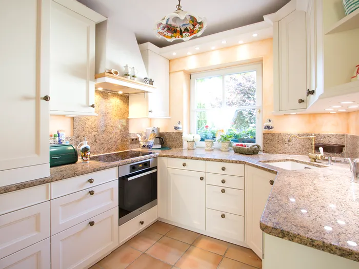 Helle, moderne Einbauküche mit weißen Schränken und Granit-Arbeitsplatten