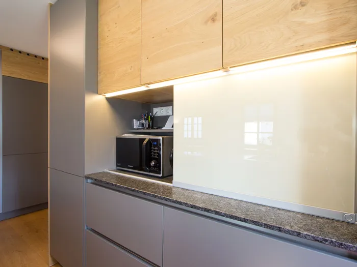 Moderne Einbauküche mit Mikrowelle, Holzoberschränken und Steinarbeitsplatte