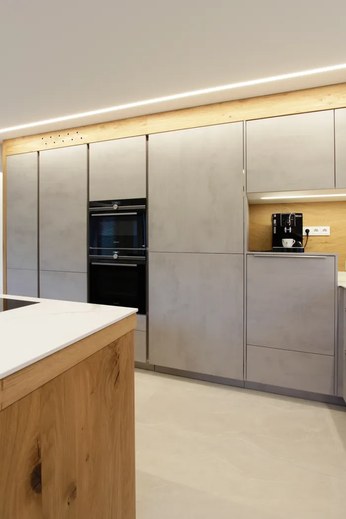 Moderne Einbauküche mit grauen Fronten, Holzakzenten und integrierter Kaffeemaschine